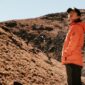 Seorang pendaki berdiri menatap megahnya gugusan puncak granit Torres del Paine di Chile yang dikelilingi lanskap subpolar liar dan danau glasial.