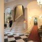 Suasana interior penginapan klasik yang mempertahankan kemegahan arsitektur era tempo dulu serta memberikan sentuhan nostalgia hangat bagi para tamu.
